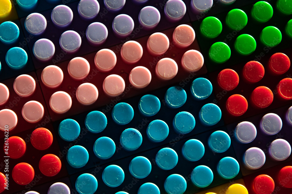 childish game background: darkened plane of plastic multi-colored bricks, blur, selective focus childish game background: darkened plane of plastic multi-colored bricks, blur, selective focus