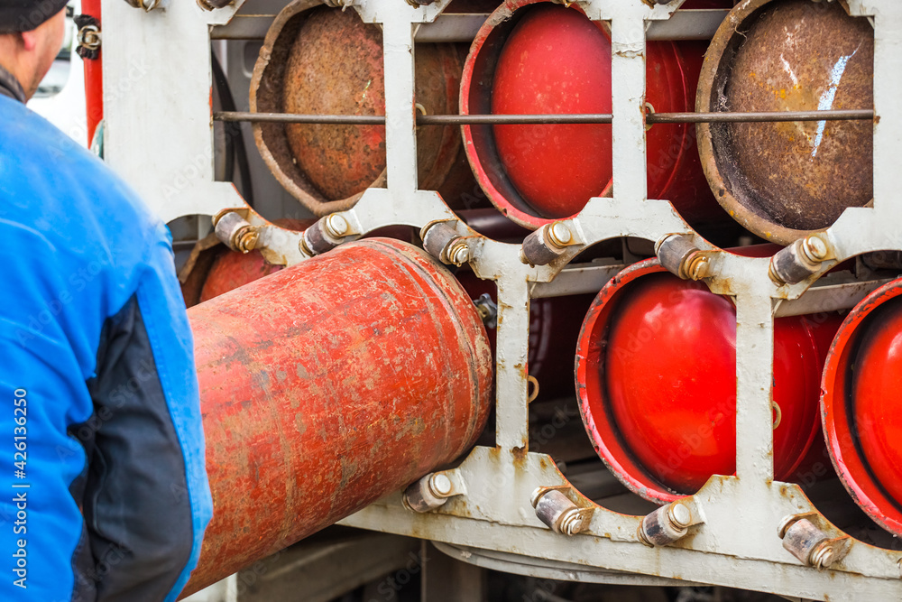Male industrial worker puts a gas cylinder into a gas machine