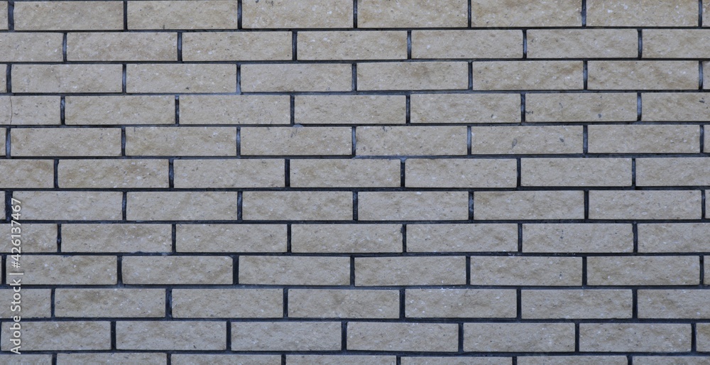 textured street wall made of gray bricks in uneven masonry image full frame, brick surface with a light shade volumetric texture, block empty backdrop graphic resource