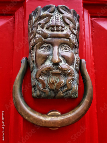 Photography Male head door knocker on Georgian red door.