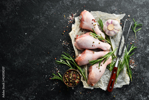 Raw chicken drumsticks with rosemary, spices and vegetables. Top view. Free space for your text.