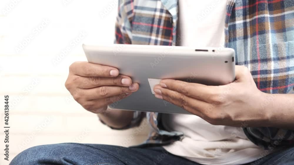 Work from home concept, young man working on digital tablet sitting on floor Work from home concept, young man working on digital tablet sitting on floor