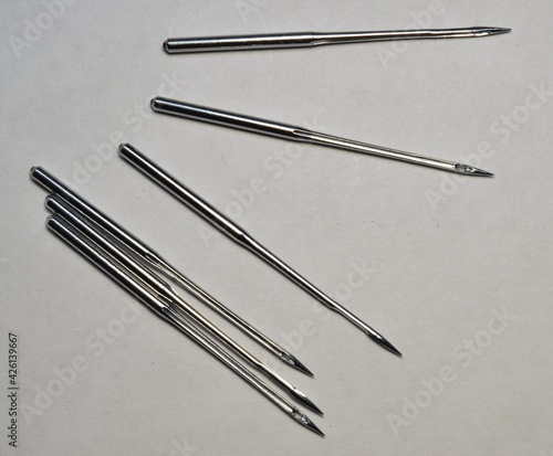 Six metal needles for the sewing machine on white background.