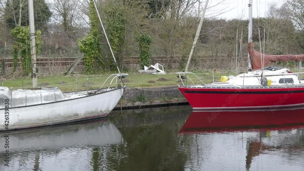 Small grungy sailboats on narrow rural countryside canal marina dolly right Small grungy sailboats on narrow rural countryside canal marina dolly right