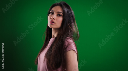 Young pretty woman in the studio posing against a green background - studio photography © 4kclips