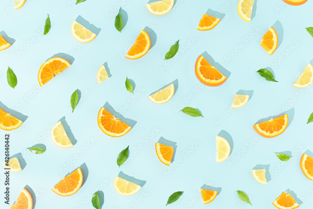 Creative fruit pattern made with slices of lemon, oranges and green leaves on bright blue background. Minimal food concept. Flat lay. Creative fruit pattern made with slices of lemon, oranges and green leaves on bright blue background. Minimal food concept. Flat lay.