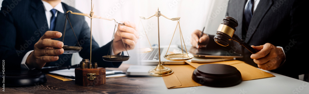 Justice and law concept.Male judge in a courtroom with the gavel, working with, computer and docking keyboard, eyeglasses, on table in morning light Justice and law concept.Male judge in a courtroom with the gavel, working with, computer and docking keyboard, eyeglasses, on table in morning light