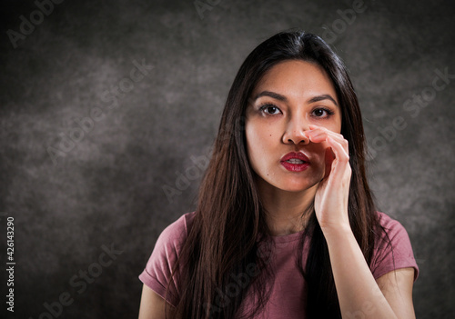 Young woman whispers something to the camera - studio photography