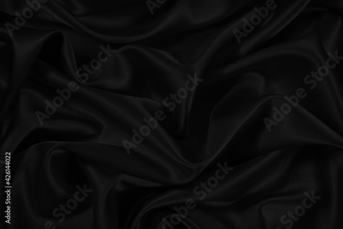 Black satin silk background. Soft wavy folds of delicate shiny fabric. Elegant background for design. Web banner. 