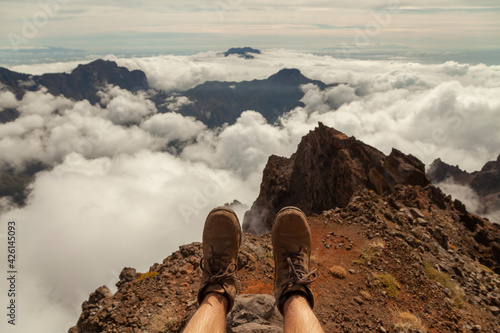 Subjective point of view shot of the landscape and hiking boots of a man, sitting on the top of the Roque de los Muchachos viewpoint, on the island of La Palma, Canary Islands, Spain. photo