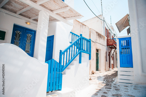The narrow streets of the island with blue balconies, stairs and flowers in Greece.