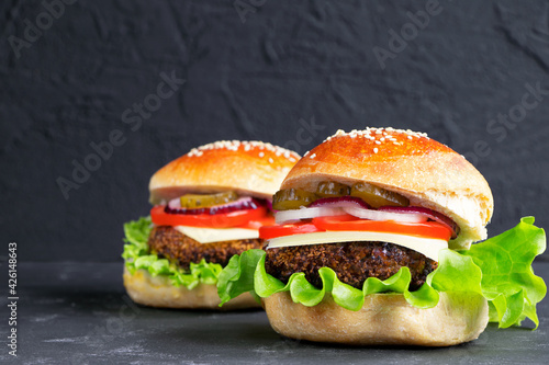 Cheeseburger on a black stone background. Hamburger with cheese. Burger isolated. Tasty Dinner.Copy space. Vertical orientation