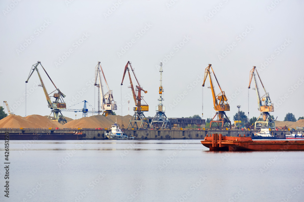 industrial river waterscape with cargo terminal and mooring barges and tugboats
