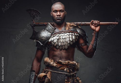 Heroic and wild soldier in steel armor with axe on his shoulders