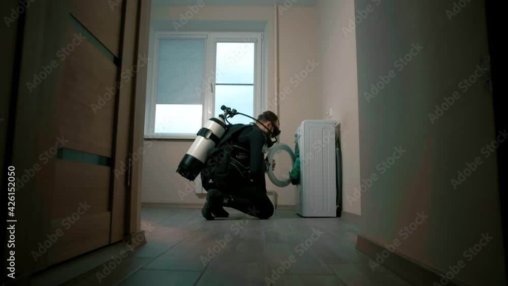 Man in diver suit to check his washing machine Stock ビデオ Adobe Stock