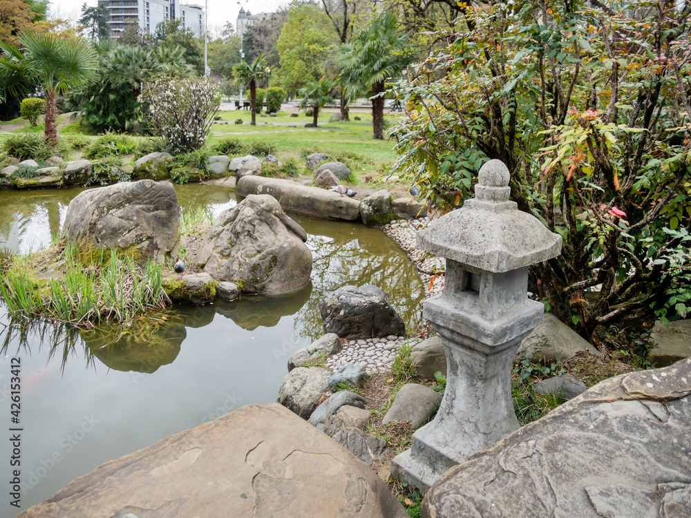 Traditional asian lantern near pond in Garden of Russian-Japanese Friendship. Urban landscaping in Sochi, Russia. Traditional asian lantern near pond in Garden of Russian-Japanese Friendship. Urban landscaping in Sochi, Russia.