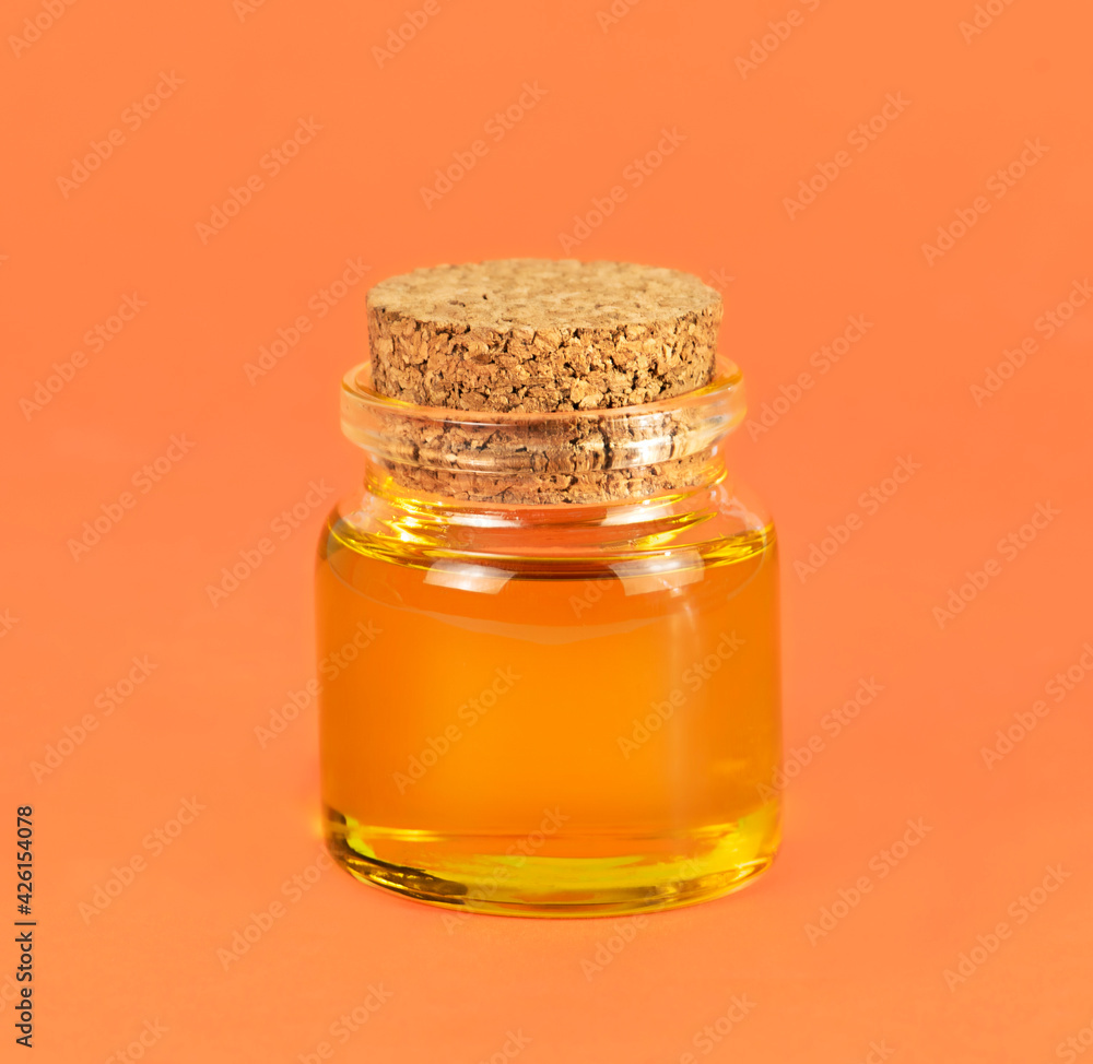 Cosmetic orange oil in a small glass jar on an orange background. Cosmetic orange oil in a small glass jar on an orange background.