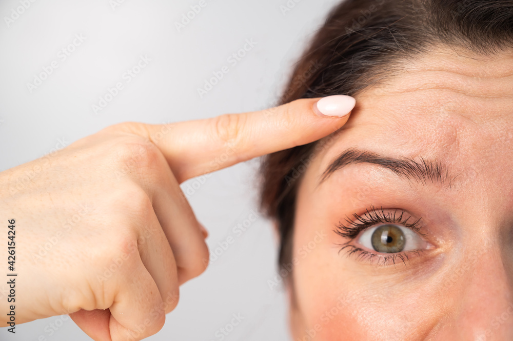 Naklejka premium Close-up portrait of Caucasian middle-aged woman showing wrinkles on her forehead. Signs of aging on the face
