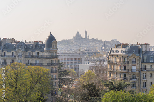 Paris, France - 04 04 2021: Park des Buttes Chaumont. View of the Sacred Heart in Montmartre district from the Temple of the Sibyl