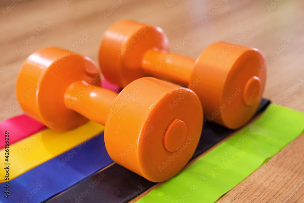 fitness rubber bands and dumbbells on a wooden background. Fitness, sport and healthy lifestyle concept. fitness rubber bands and dumbbells on a wooden background. Fitness, sport and healthy lifestyle concept.