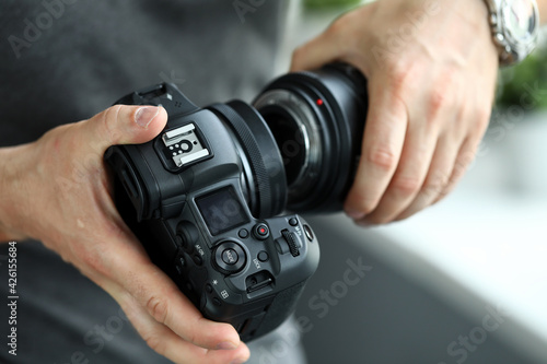 Male hands putting on modern digital camera professional lens