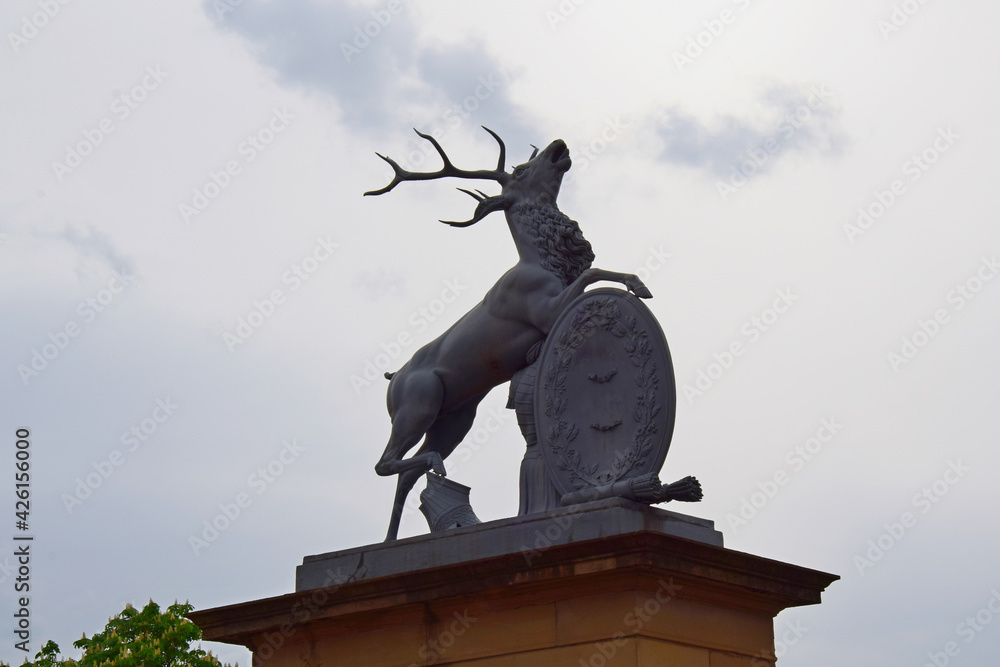 Deer statue with hunting objects on the sky background