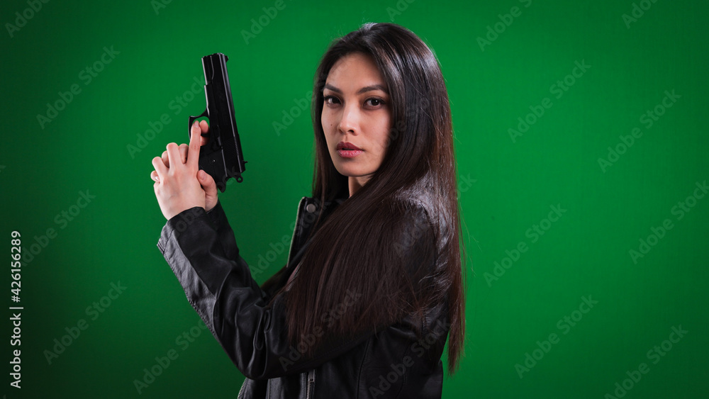 Young female agent with a gun in her hand looks at the camera - studio photography Young female agent with a gun in her hand looks at the camera - studio photography