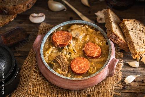 Christmas cabbage soup in ceramic bowl on natural wooden background.