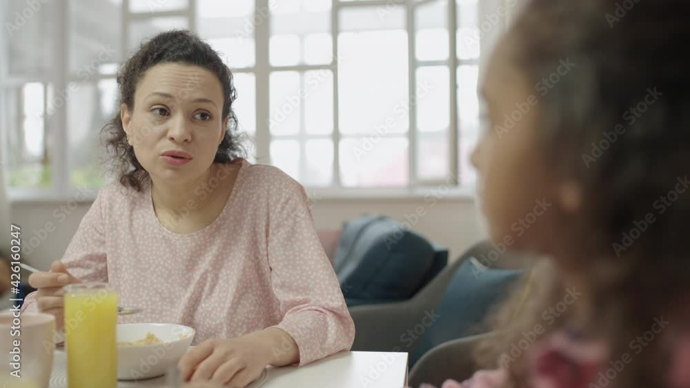 Woman talking to teen daughter at table family eating breakfast, morning routine Woman talking to teen daughter at table family eating breakfast, morning routine