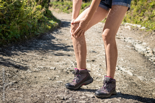Tourist injured during hike. Woman feeling knee pain. Female hiker having health problem