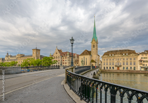 Beautiful view of historic city center of Zurich with famous Fraumunster Church and Munsterbucke crossing river Limmat on a sunny day with blue sky and clouds in summer, Canton of Zurich, Switzerland