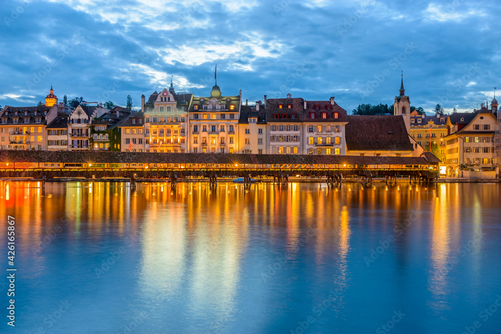 Fototapeta premium Night view towards Chapel Bridge (Kapellbruecke) together with the octagonal tall tower (Wasserturm) it is one of the Lucerne's most famous tourists attraction