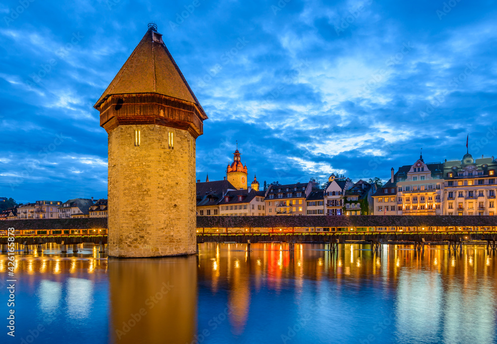 Fototapeta premium Night view towards Chapel Bridge (Kapellbruecke) together with the octagonal tall tower (Wasserturm) it is one of the Lucerne's most famous tourists attraction