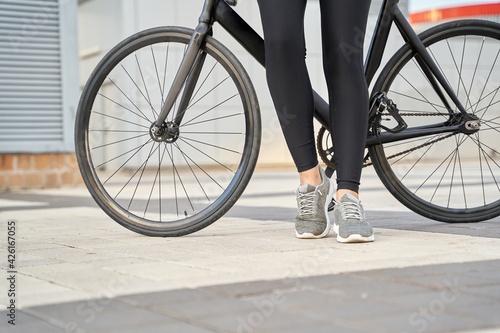 Young woman with black bike in the city