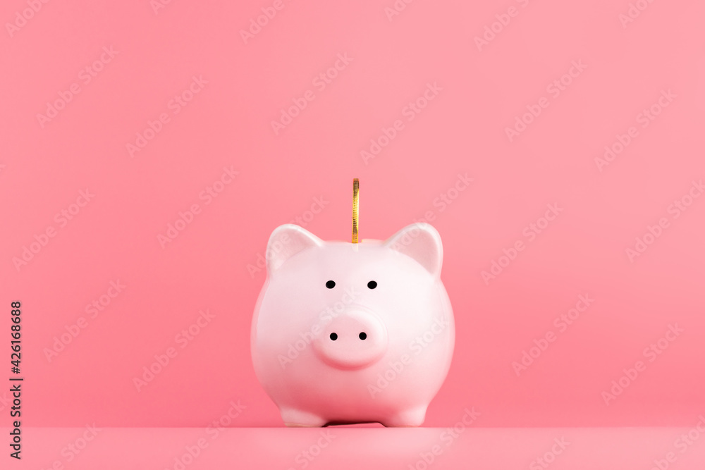 Pink piggy Bank with a coin stands in the center on a pink background. Online business shopping concept - obrazy, fototapety, plakaty 