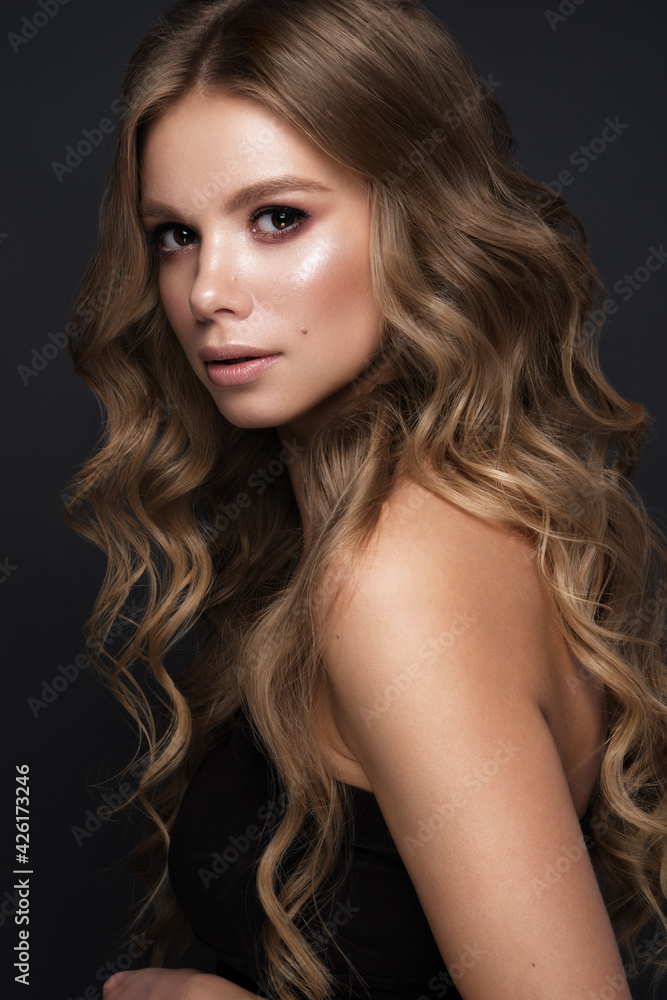 Fototapeta premium Beautiful blond girl with a perfectly curls hair, and classic make-up. Beauty face and hair.