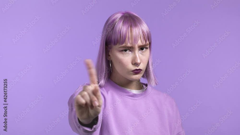 Portrait of serious trendy woman showing rejecting gesture by stop finger sign. Girl isolated on violet background. Portrait of serious trendy woman showing rejecting gesture by stop finger sign. Girl isolated on violet background.