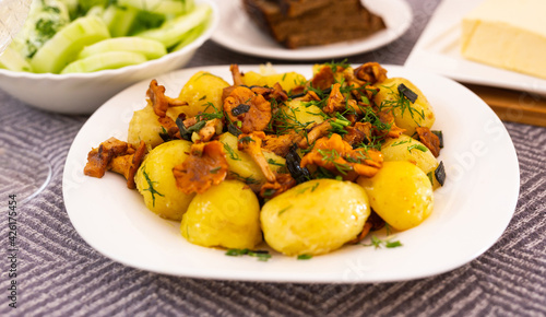 baked  potatoes with chanterelles, served with herbs on white plate