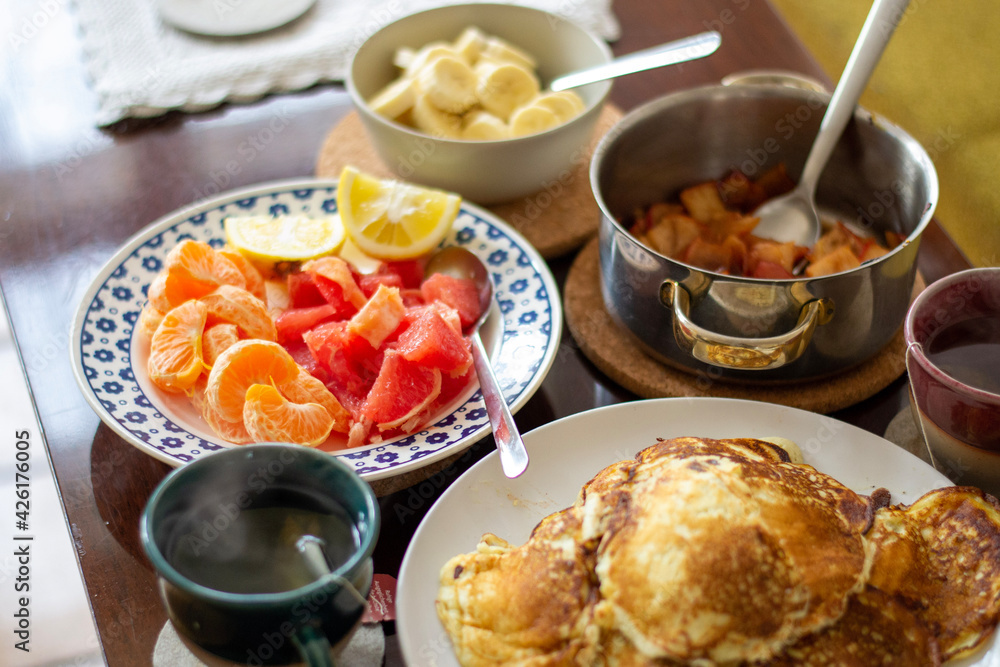 Brunch pancakes with citrus fruits, homemade apple jam, bananas and steaming, hot cup tea or coffee. Brunch pancakes with citrus fruits, homemade apple jam, bananas and steaming, hot cup tea or coffee.