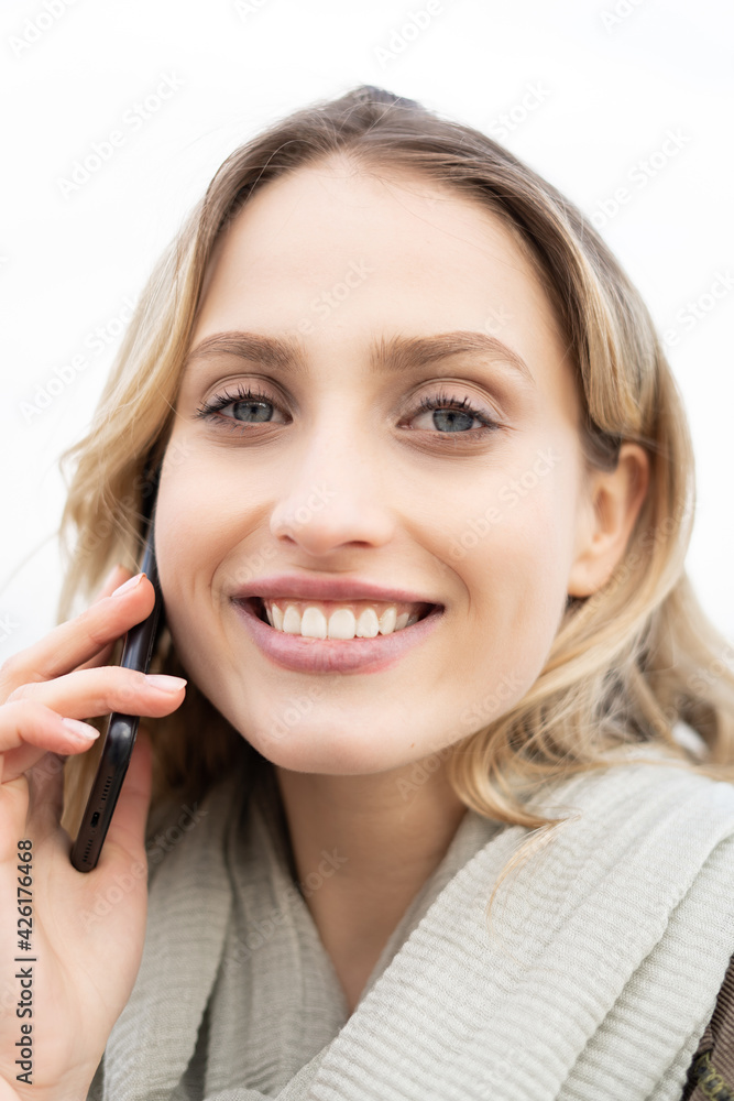 Close up portrait of a happy blonde girl smiling and talking on the mobile phone with a stunning look of her blue eyes Close up portrait of a happy blonde girl smiling and talking on the mobile phone with a stunning look of her blue eyes