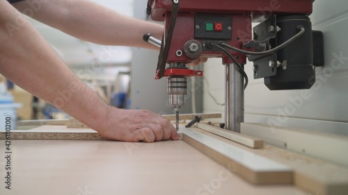 The process of manufacturing cabinet furniture from chipboard on a modern automatic drilling and milling machine. Modern automatic woodworking machine. Drilling machine in the furniture industry.