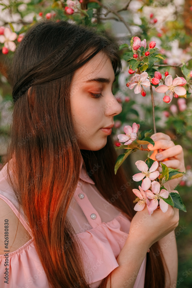 Beauty portrait redhead woman in spring in the branches of an apple trees Beauty portrait redhead woman in spring in the branches of an apple trees