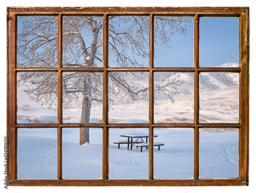 picnic table covered by fresh snow at foothills of Rocky Morning as seen from a vintage sash window