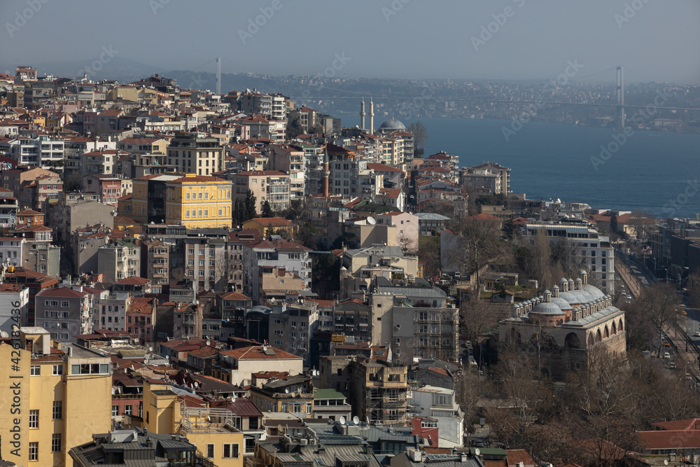 View from Galata Tower of Besiktas district in Istanbul, Bosphorus Bay, Eminonu district. You can see dense urban development, brown tiles on the roofs, mosques, streets filled with urban transport