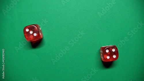 Red dice falling on green table. The Numbers 4 and 3 Appear on the Dice.