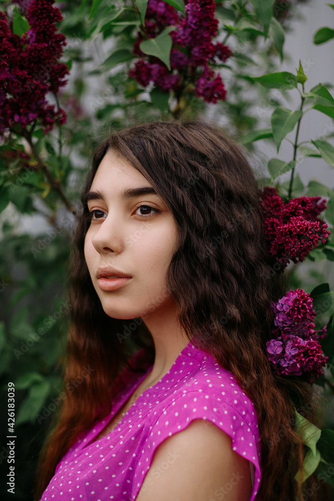 Young redhead girl standing near lilac bushes in the park Young redhead girl standing near lilac bushes in the park