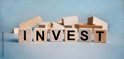 The inscription INVEST on wooden cubes isolated on a light background, the concept of business and finance.