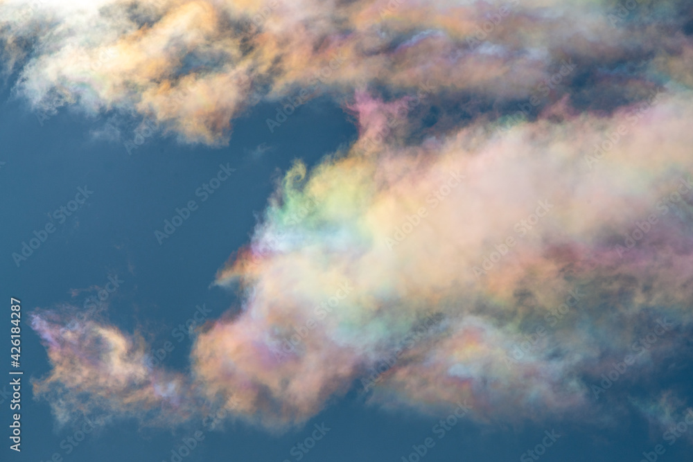 Unique phenomena of iridescent clouds with rainbow colors in natural form. Blue sky with colourful clouds in front. 