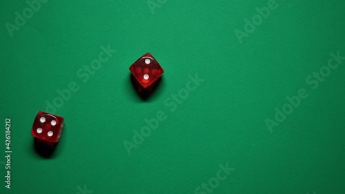 Red dice falling on green table. The Numbers 4 and 2 Appear on the Dice.
