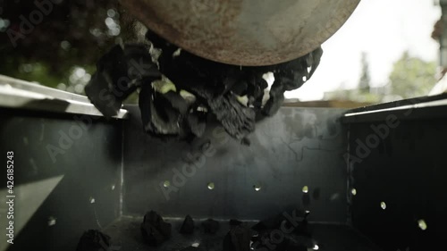 Charcoal from the bag is poured into the grill for lighting and barbecue in nature. Concept of fuel and outdoor recreation in summer in warm weather